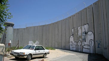 The graffiti-marked West Bank wall with a white car in front