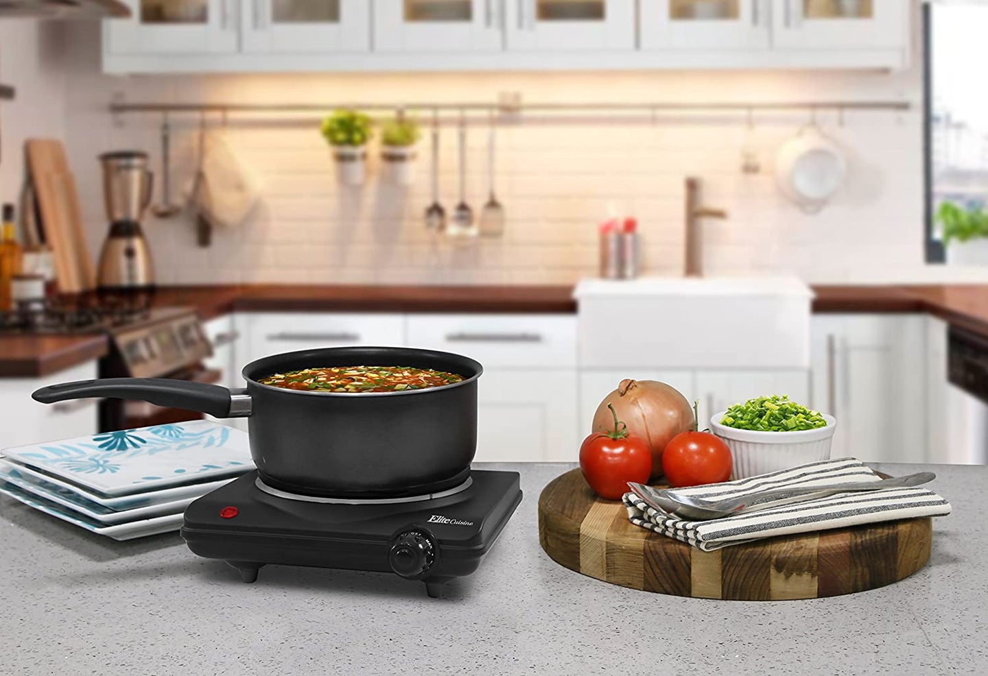 induction cooktop on a kitchen counter with plates and vegetables