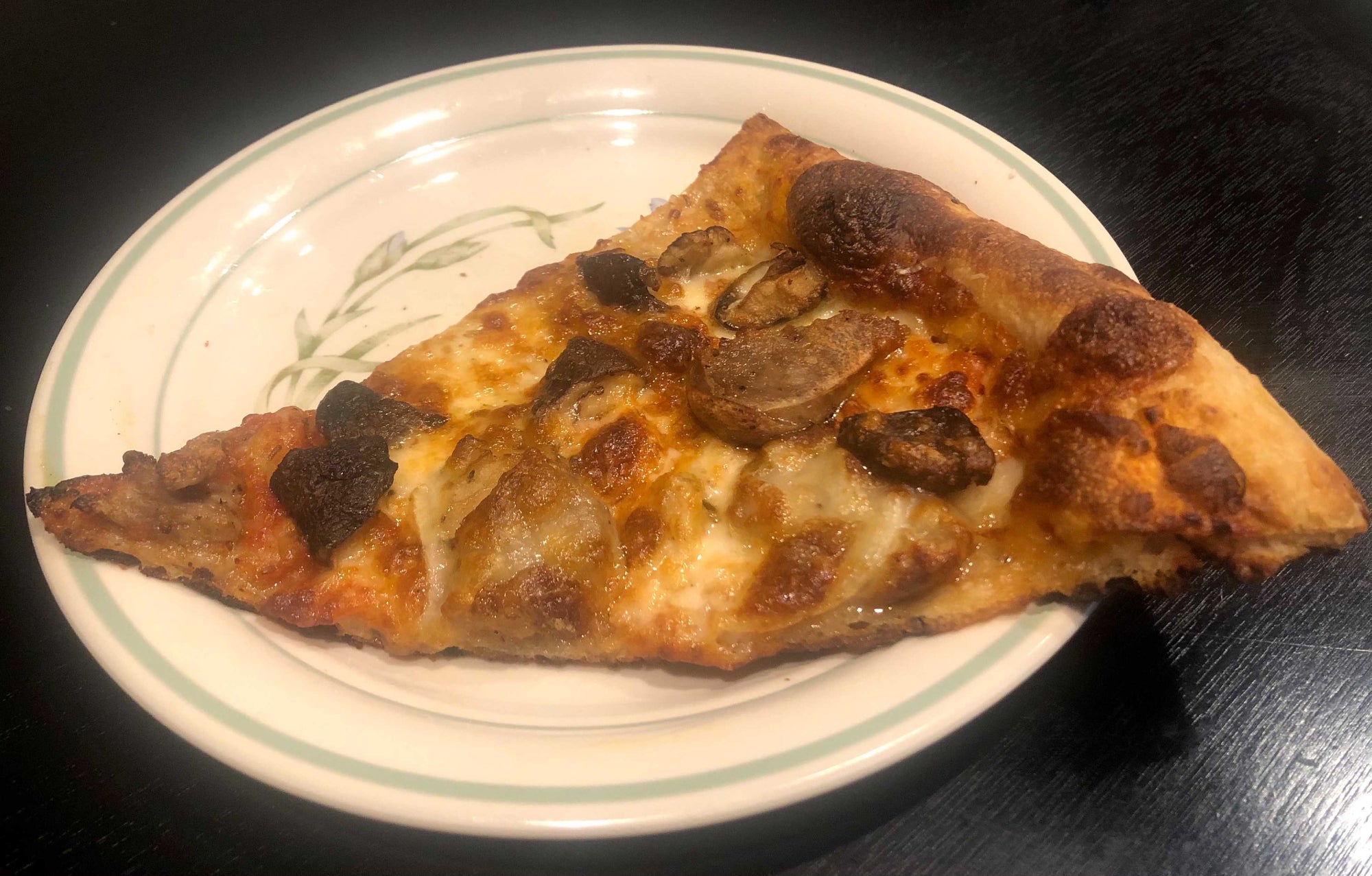 A slice of sausage, mushroom, and onion pizza that someone chose to reheat in an air fryer.