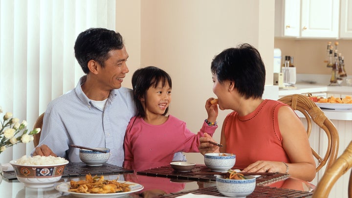 Chinese parents and kid have a meal in their dining room