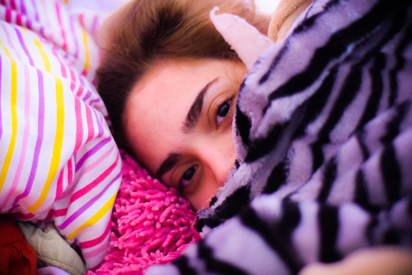 woman surrounded by color pink and purple blankets