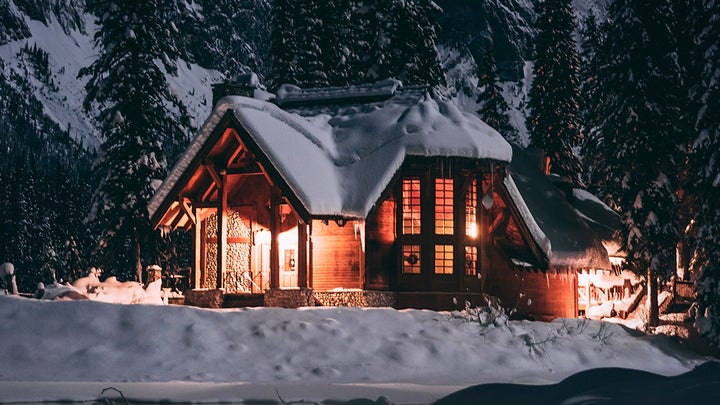 house with lights on covered in snow on a mountain
