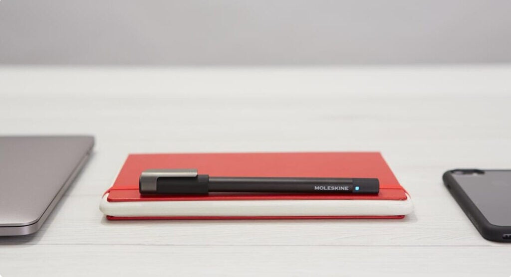 A black Moleskine pen and red tablet notebook that can be used to digitize handwritten notes.