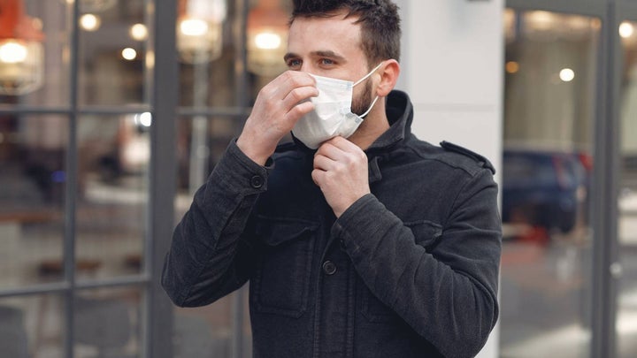Bearded man wearing a surgical mask on the street