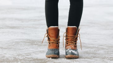 person in brown winter boots standing on a snowy and icy ground