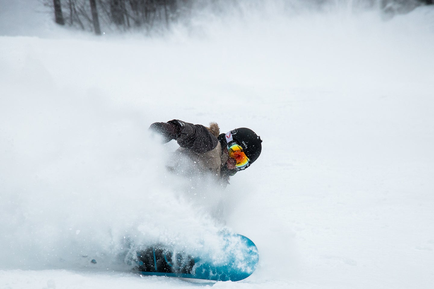 person snowboarding with helmet and the best snowboard goggles and carving through some snow