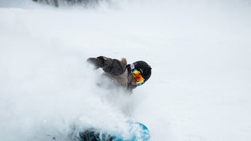 person snowboarding with helmet and the best snowboard goggles and carving through some snow