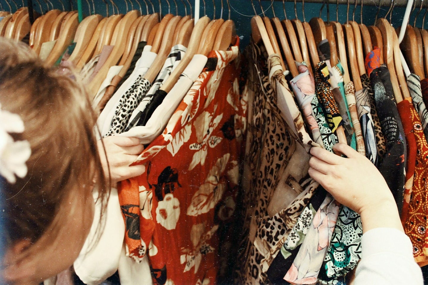 Woman searching through rack of vintage second-hand thrift clothing.