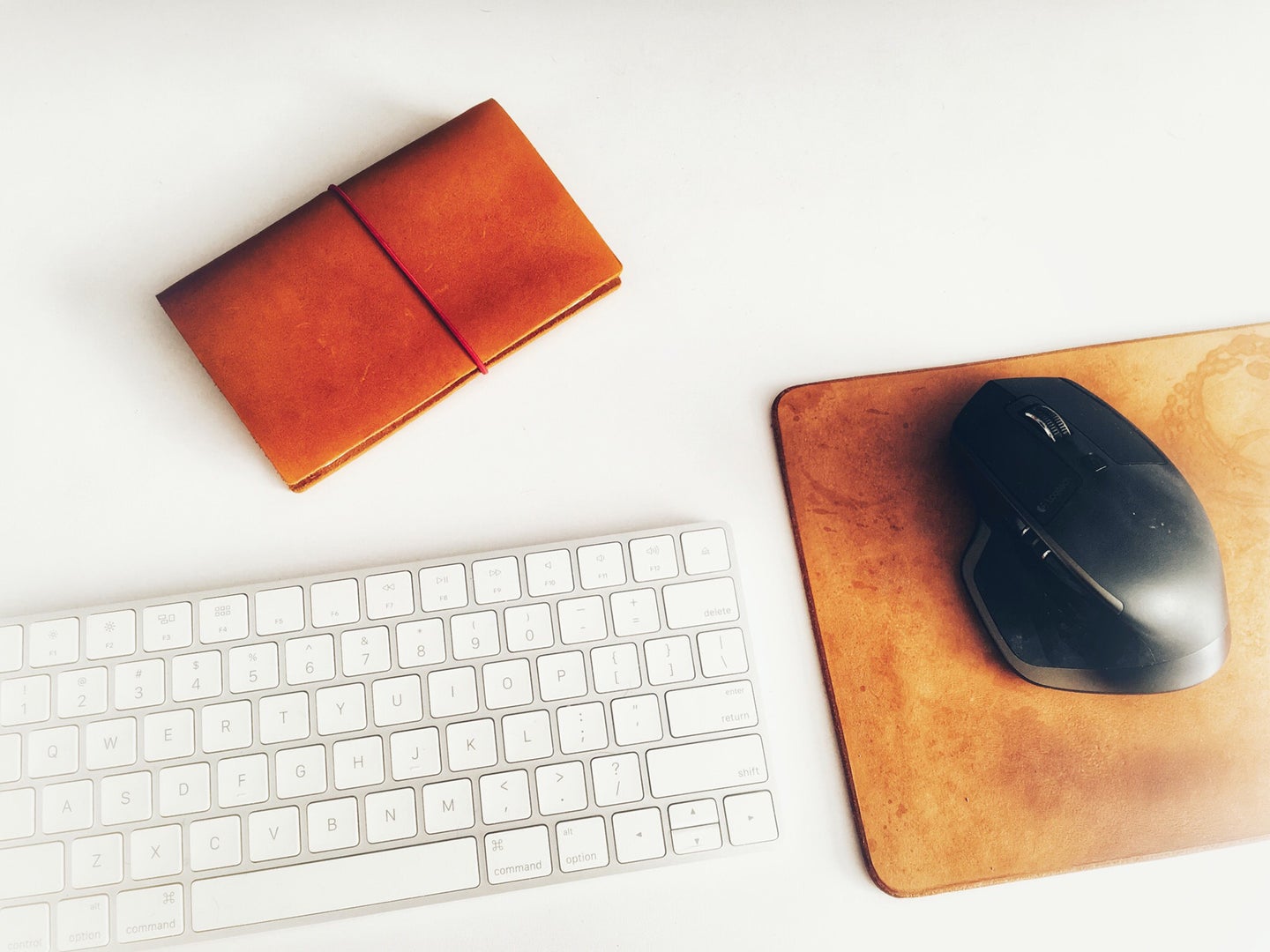 keyboard, leather mouse pad, and mouse on a white surface
