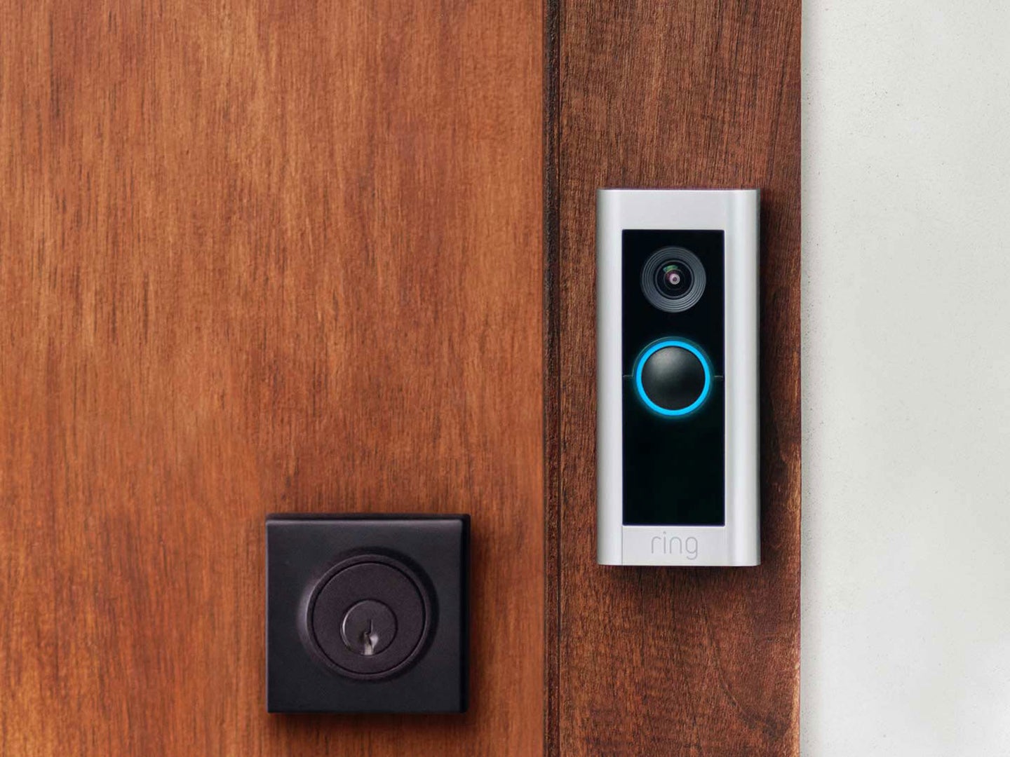 Ring Video Doorbell Pro 2 installed on a brown wooden door near a deadbolt lock.