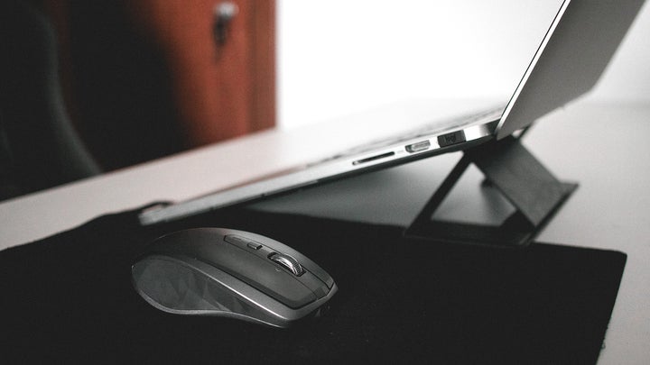 mouse no a black mousepad next to an apple macbook