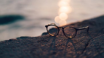 glasses near water with the sun casting a shadow