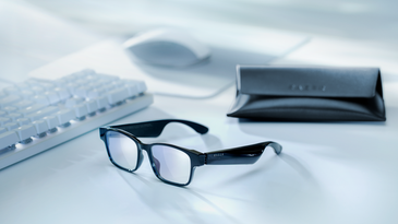 Razer Anzu Smart Glasses sitting on a desk with accessories.