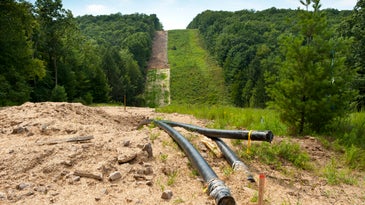 A gas pipeline under construction in a clear-cut strip of forest