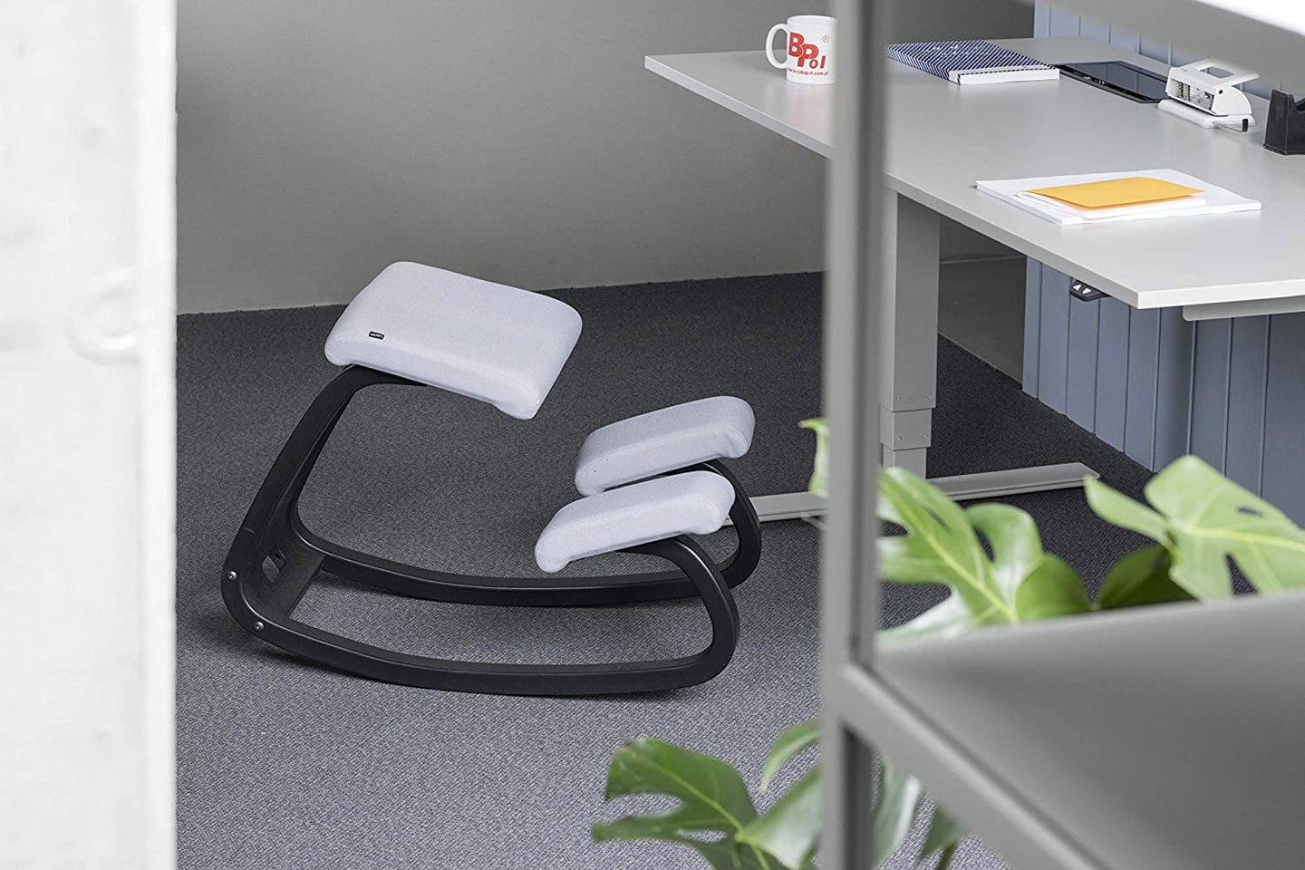 black and grey kneeling chair next to a silver desk