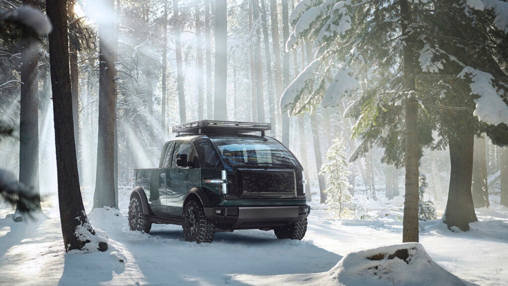 Canoo electric pickup truck chilling in the woods with sun rays coming through the trees