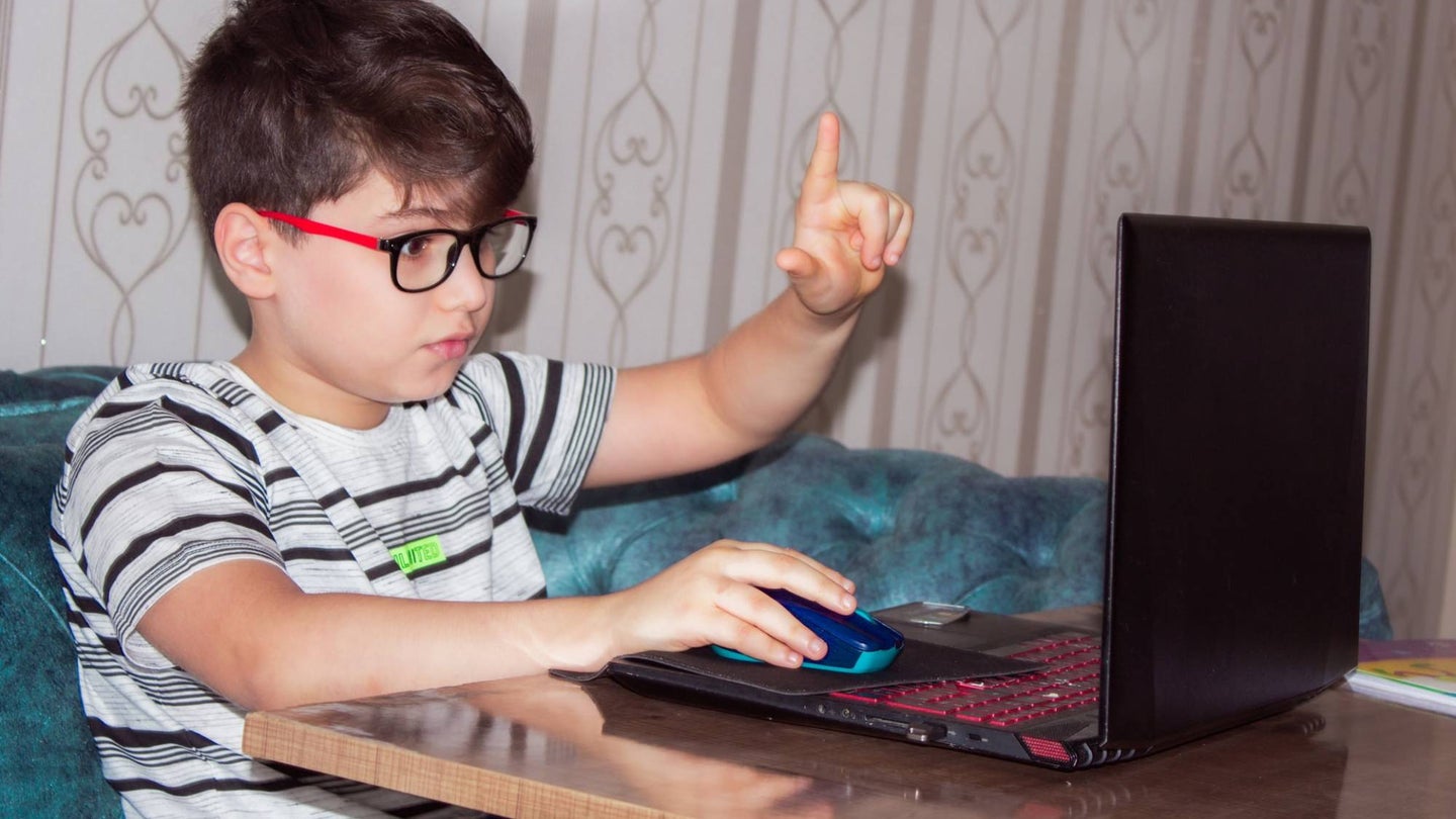 Kid with glasses using computer in a living room
