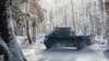 Canoo electric pickup truck driving through snow with a roof rack