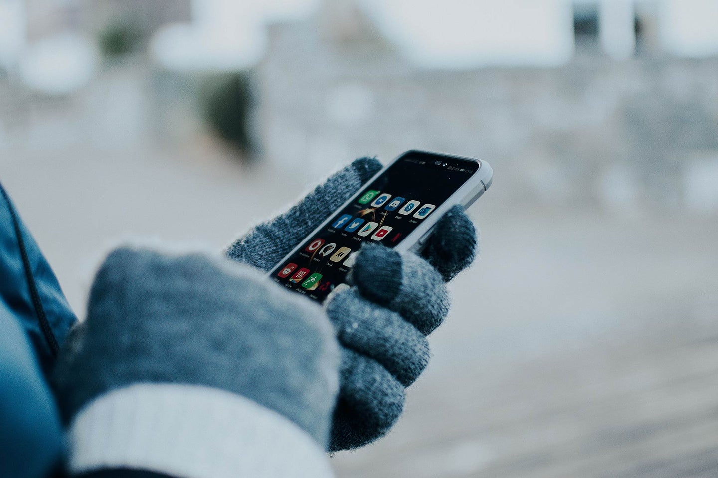 Person wearing gloves using an iPhone