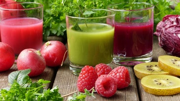 Glasses of juice, smoothies, and berries on a table.