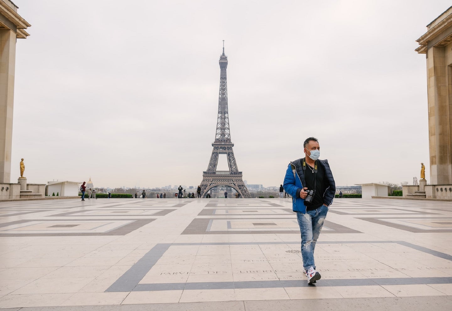Tourist in surgical mask in front of the Eiffel Tower