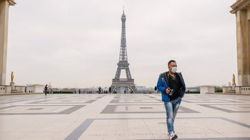 Tourist in surgical mask in front of the Eiffel Tower