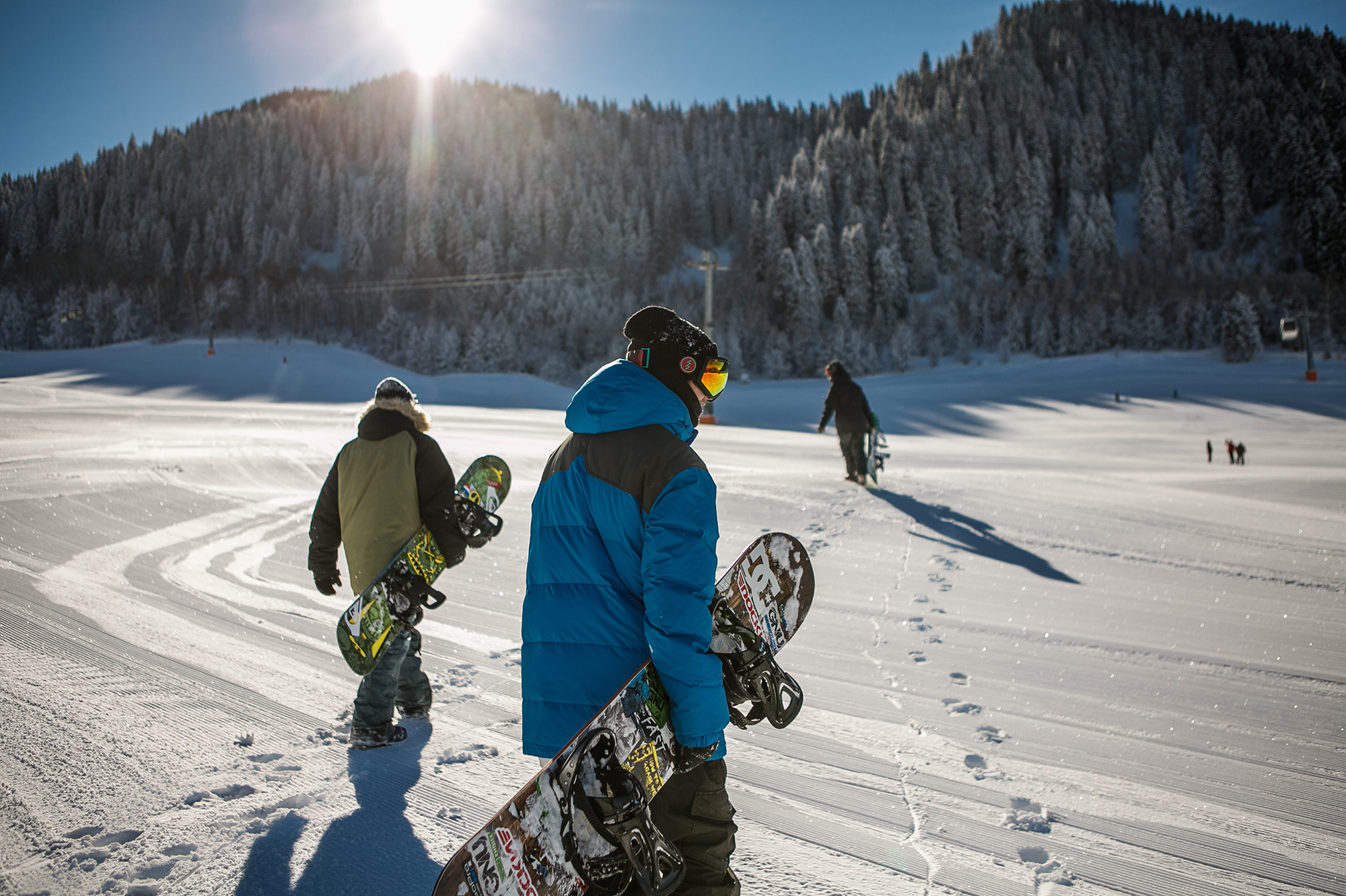 three people with snowboards walking on a snowy moutain