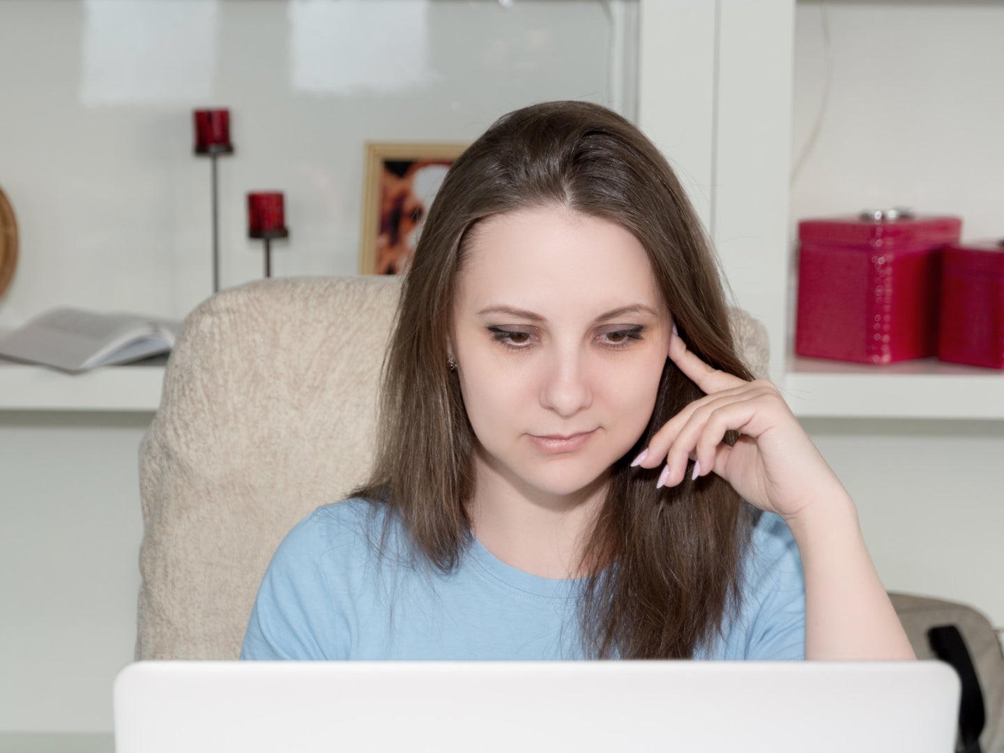 A woman sitting behind a laptop, looking somewhat amused.
