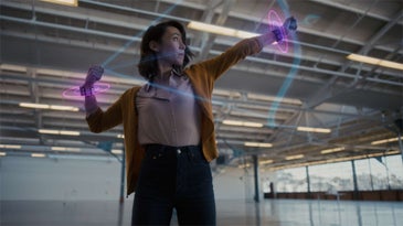 A woman pulling back a virtual bow to shoot an arrow while wearing Facebook's prototype haptic feedback wrist devices