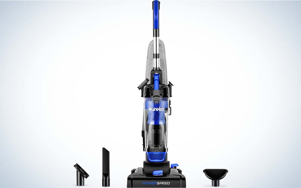 The Eureka Uprgith Vacuum Cleaner, which is gray and blue, and black, with some attachments in the foreground against a plain background.