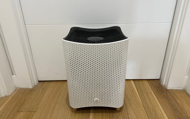 Mila smart air purifier on a light wooden floor in front of a closed white door