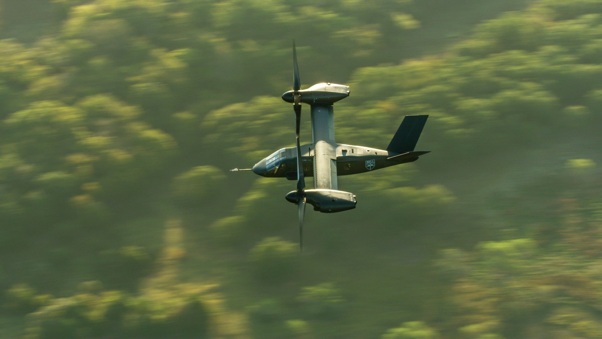A V-280 Valor flying over a forest.