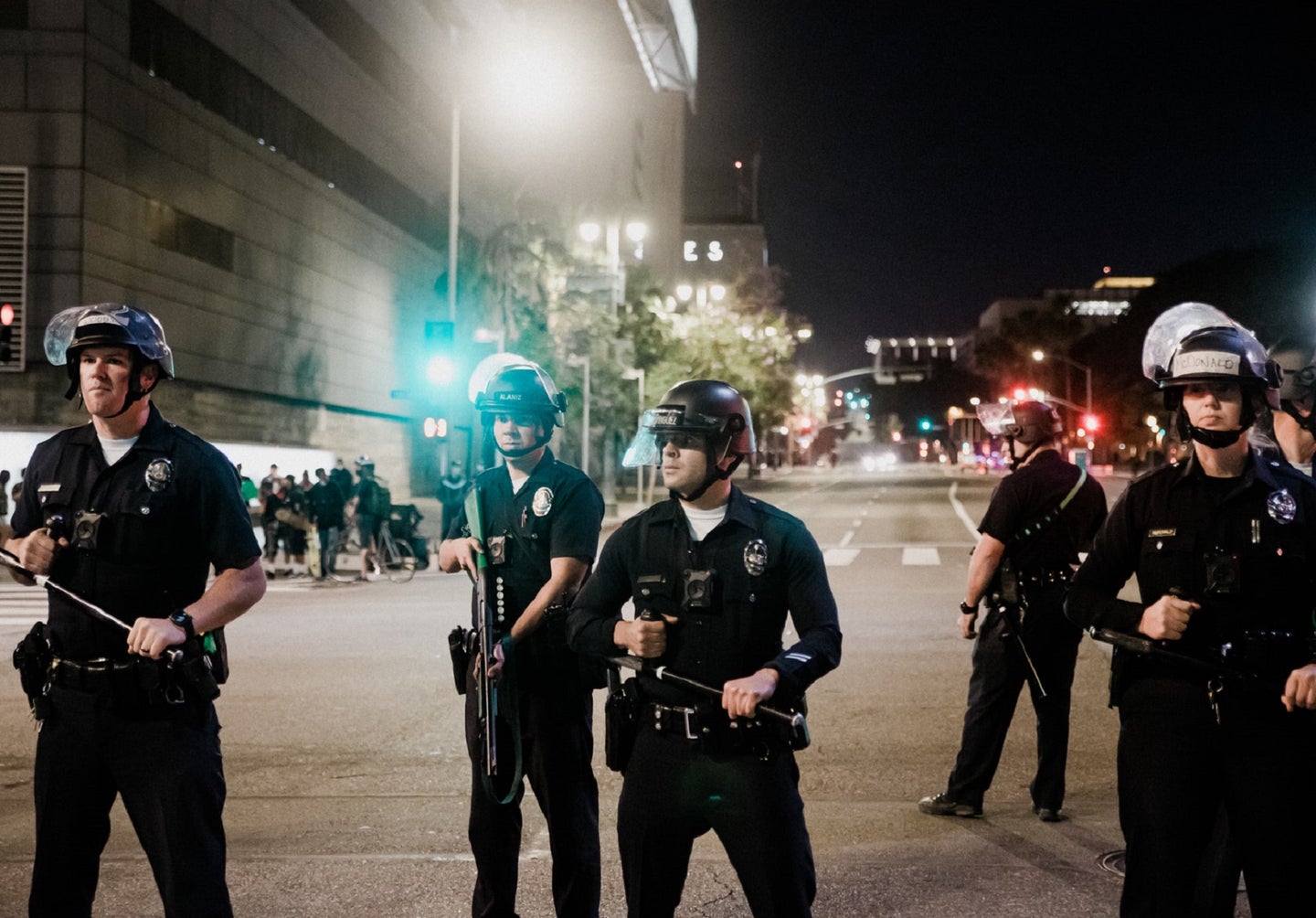 LAPD officers with batons and helmets on the street at night