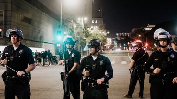 LAPD officers with batons and helmets on the street at night