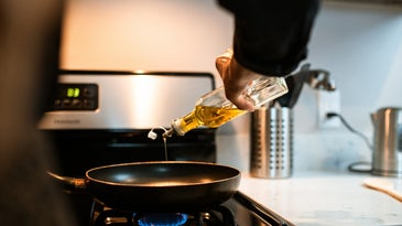 person pouring olive oil into a pan