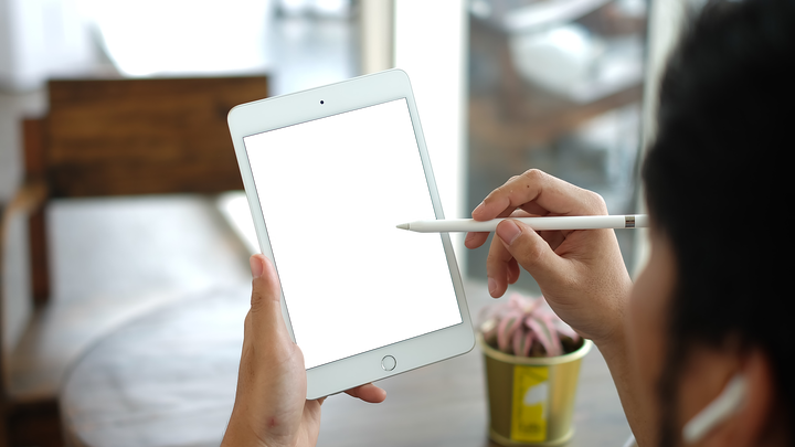 A person putting an Apple Pencil on a blank iPad Mini screen.
