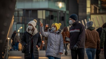 people wearing masks walking down a street