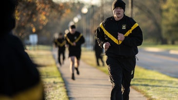 Army cadet running in a black and yellow sweatsuit on a sidewalk