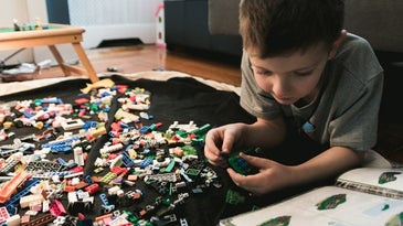 Thinking kid trying to form different size and colored puzzle.
