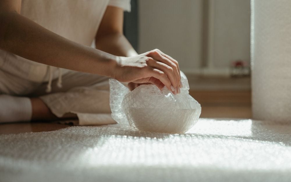 Person wrapping a bowl with a bubble wrap
