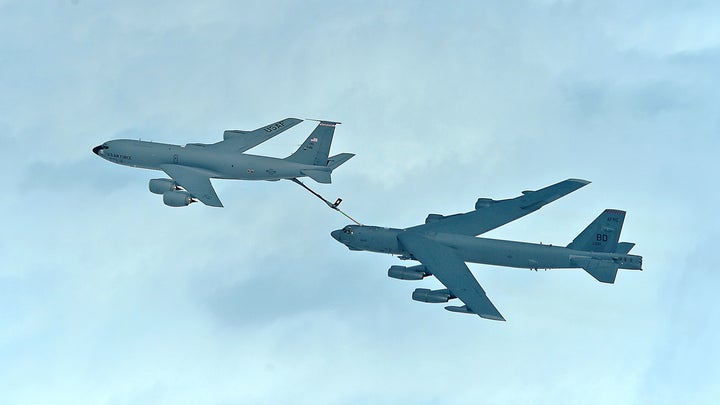 A bomber is refueled behind a tanker airplane.