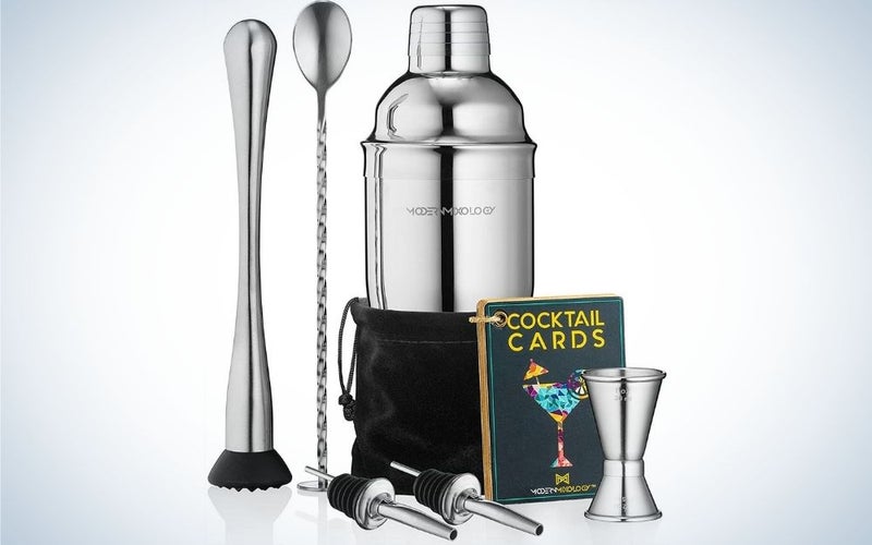 A silver cocktail shaker set drink mixer with portable Bartender Kit with 24oz Martini shaker bar tool set, 2 pourers, muddler, jigger, mixing spoon and velvet bag in front of it.