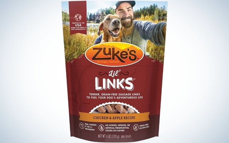AZuke's Lil' Links Grain Free Dog Treats Chicken & Apple recipe in a cherry-colored packaging and with a picture of a man by his side with his dog.