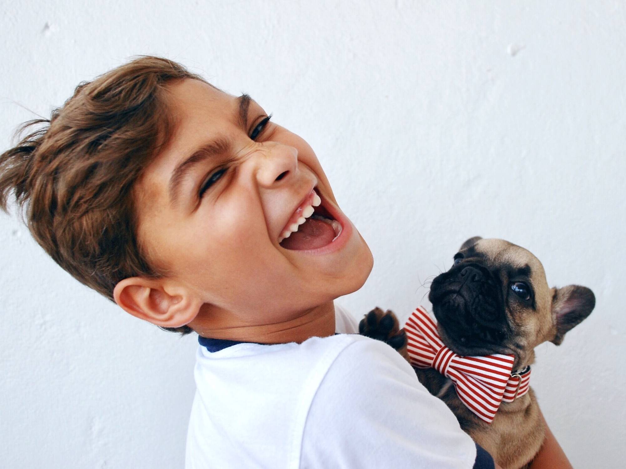 kid holding puppy laughing