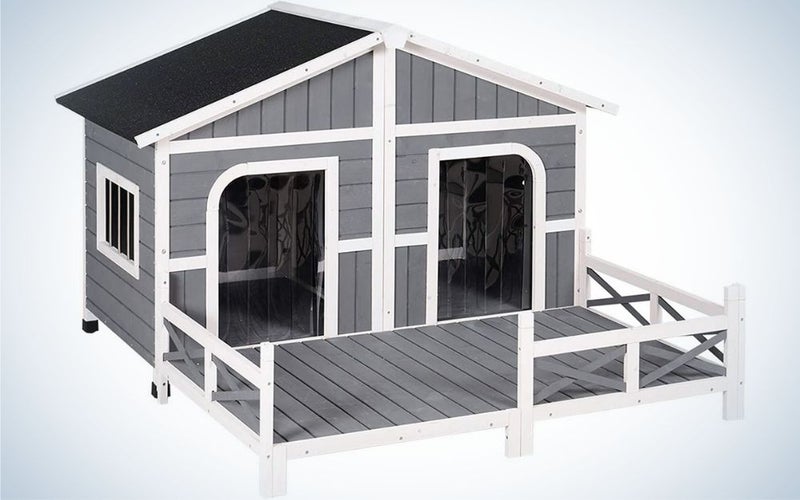 A grey with black roof wooden outdoor dog house with two doors in it.