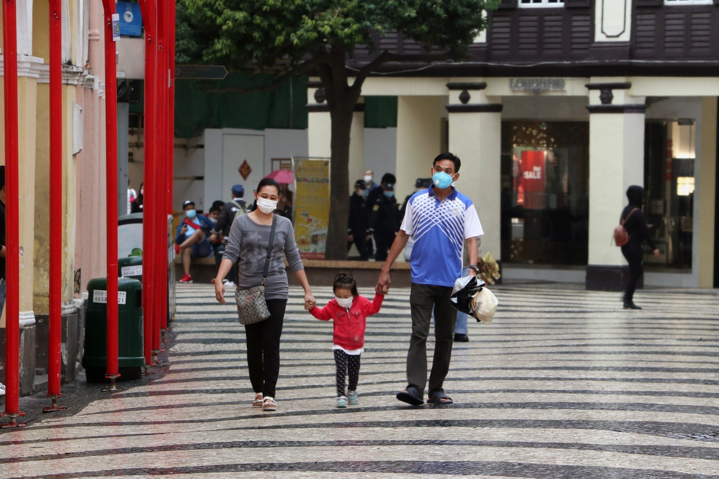 Two adults and a child walk wearing masks.