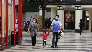 Two adults and a child walk wearing masks.