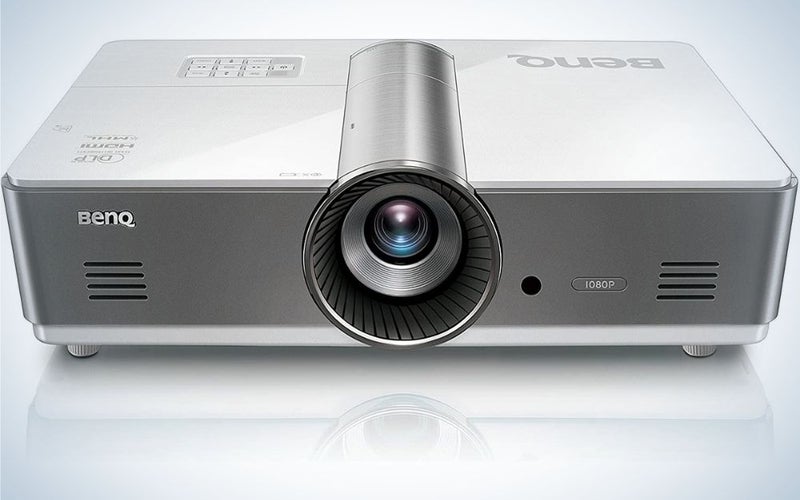 A grey square business projector with a blue lens in the middle of it.