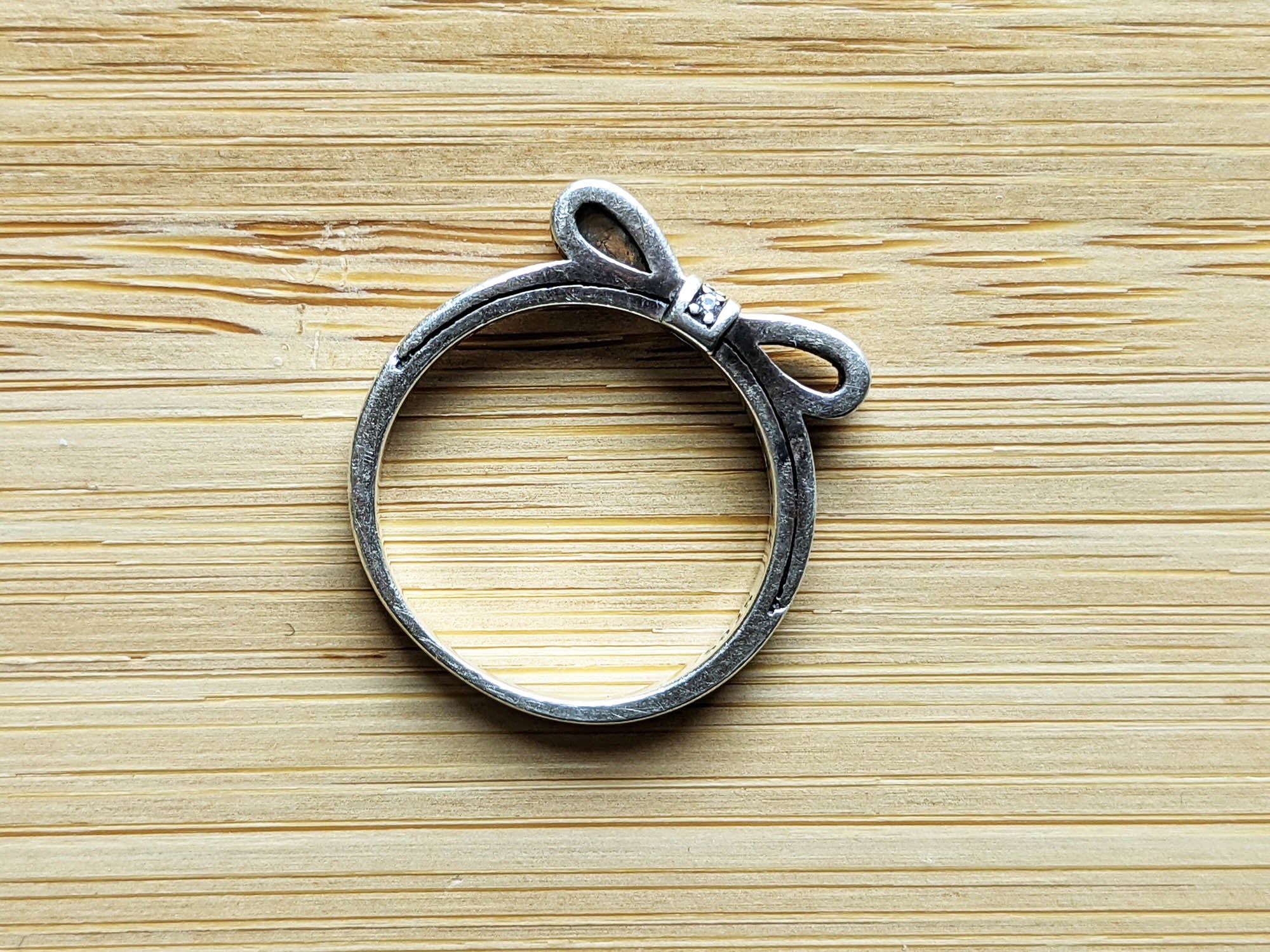 A silver ring on a light-colored wooden table.