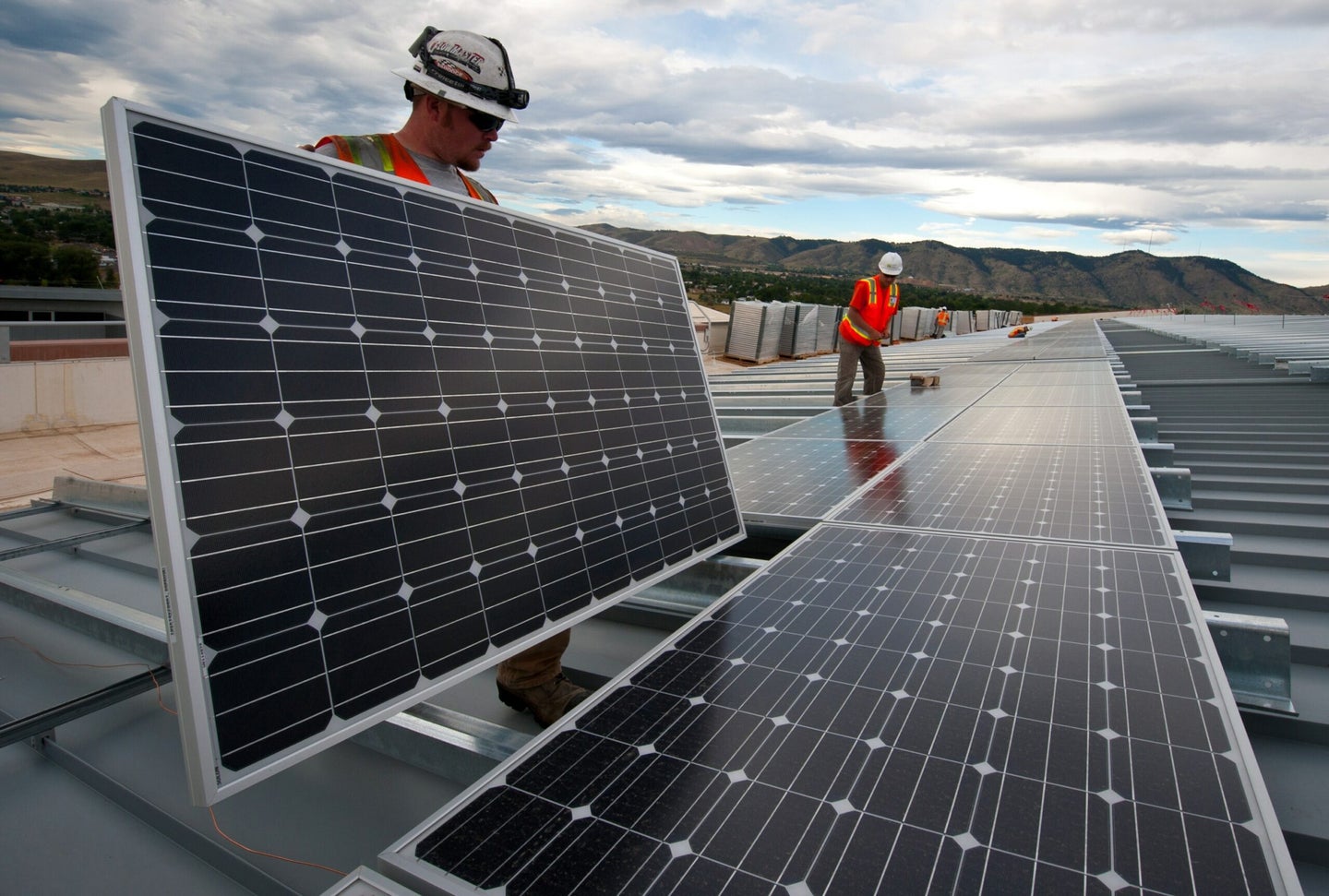 Construction workers install solar panles.